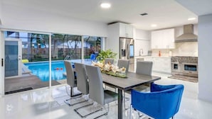 Una cocina moderna con armarios blancos, un horno de acero inoxidable y un comedor con mesa y sillas.