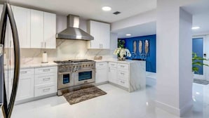 Una cocina moderna con muebles blancos, una campana extractora de acero inoxidable y una pared de acento azul.