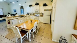 Une cuisine compacte avec des meubles blancs, un îlot central doté de chaises, un four à micro-ondes et un réfrigérateur.