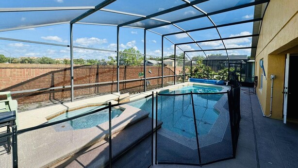 Une piscine extérieure couverte, dotée d’un toit en métal et offrant une vue sur un quartier résidentiel.