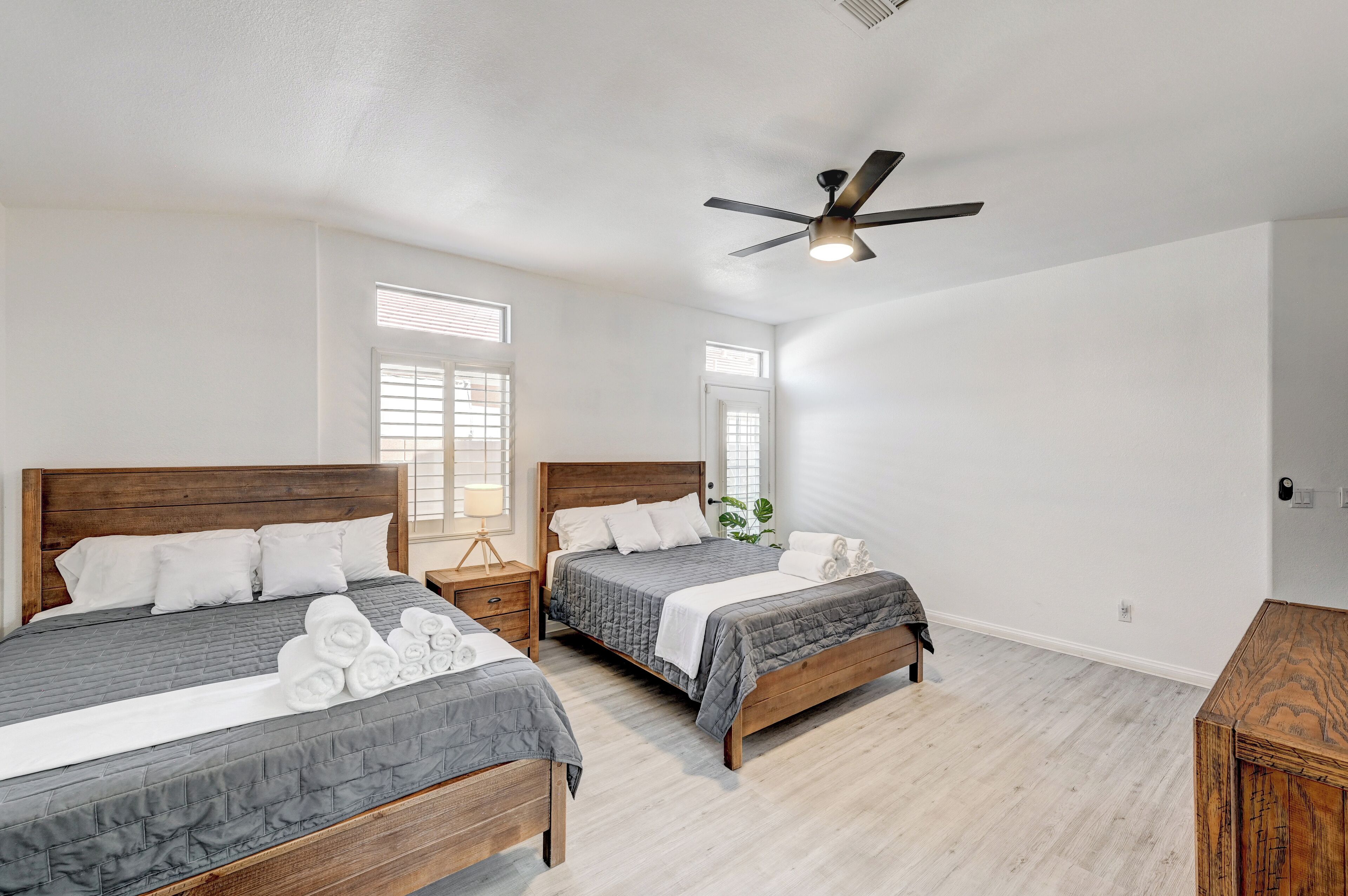 A bedroom with two beds, a ceiling fan, and a wooden nightstand.