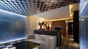 Una hall moderna di un hotel con pavimento a scacchi, un divano, un tavolino da caffè e una parete decorata.