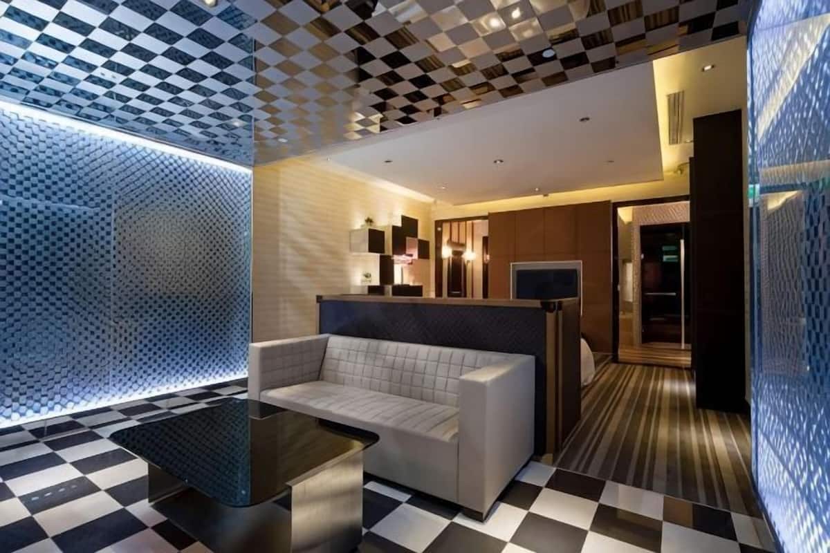A modern hotel lobby with a checkered floor, a sofa, a coffee table, and a patterned wall.