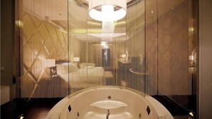 Un bagno moderno con una vasca da bagno ampia, un lampadario e un pannello decorativo.