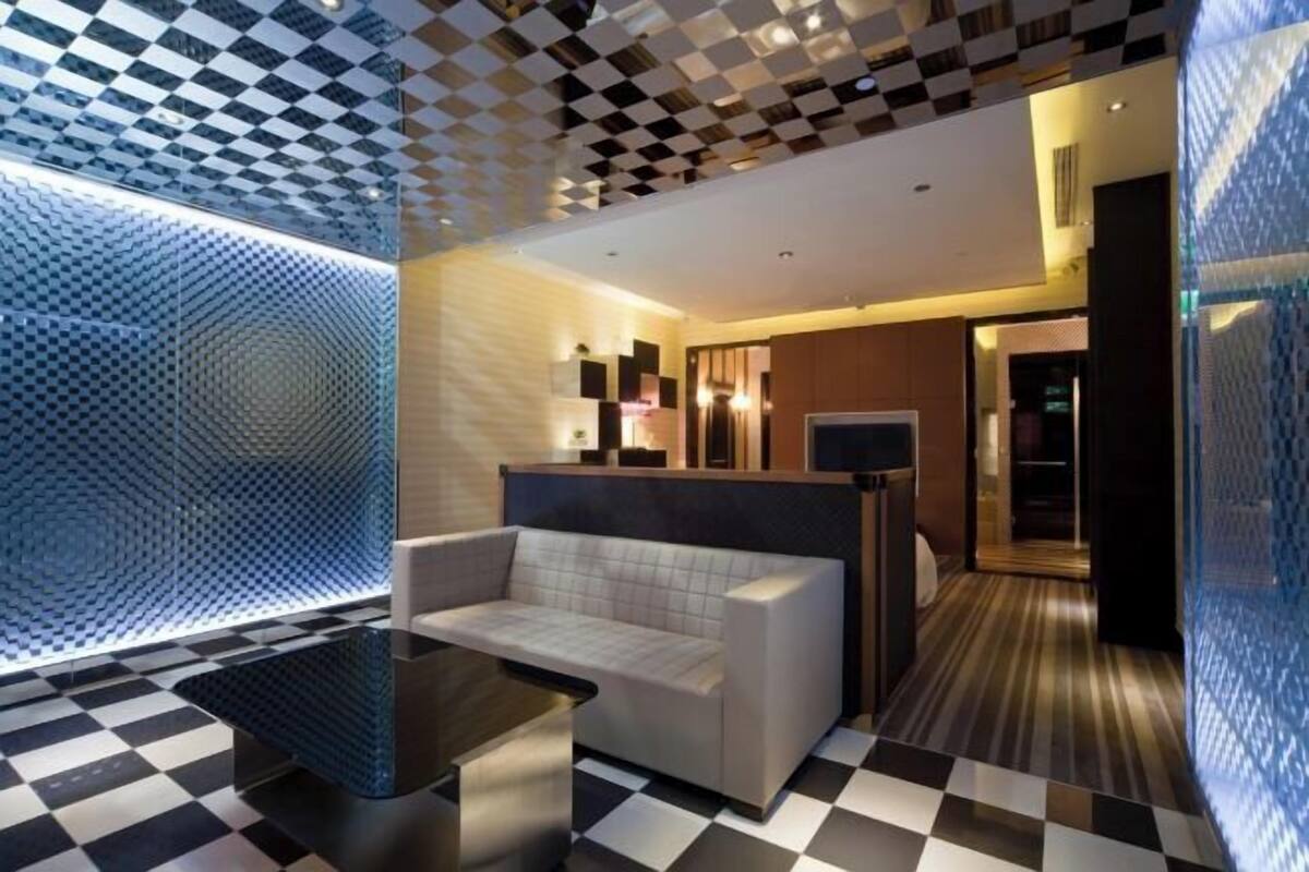 A modern hotel lobby with a checkered floor, a sofa, and a patterned wall.
