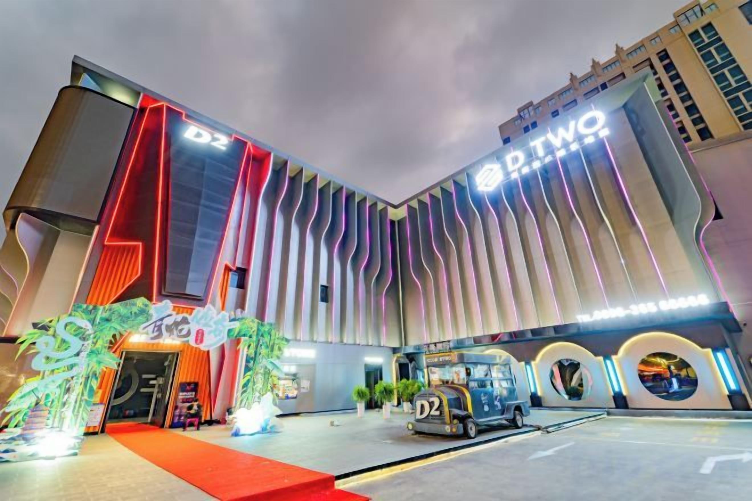 A hotel with a modern facade, a prominent 'D2' sign, and a red carpet entrance.