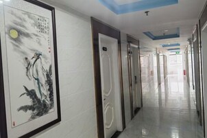 A corridor with doors, a framed artwork on the wall, and a ceiling with recessed lighting.