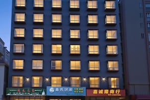 Un edificio de hotel de varios pisos con ventanas iluminadas y varios establecimientos comerciales en la planta baja.