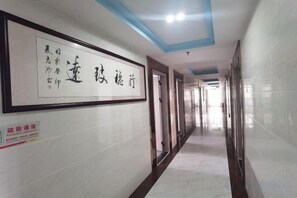A corridor with a framed sign on the wall, doors on both sides, and a tiled floor. - Jiayan Runguo Hotel (Danzhou Summer Square Branch) (Danzhou)