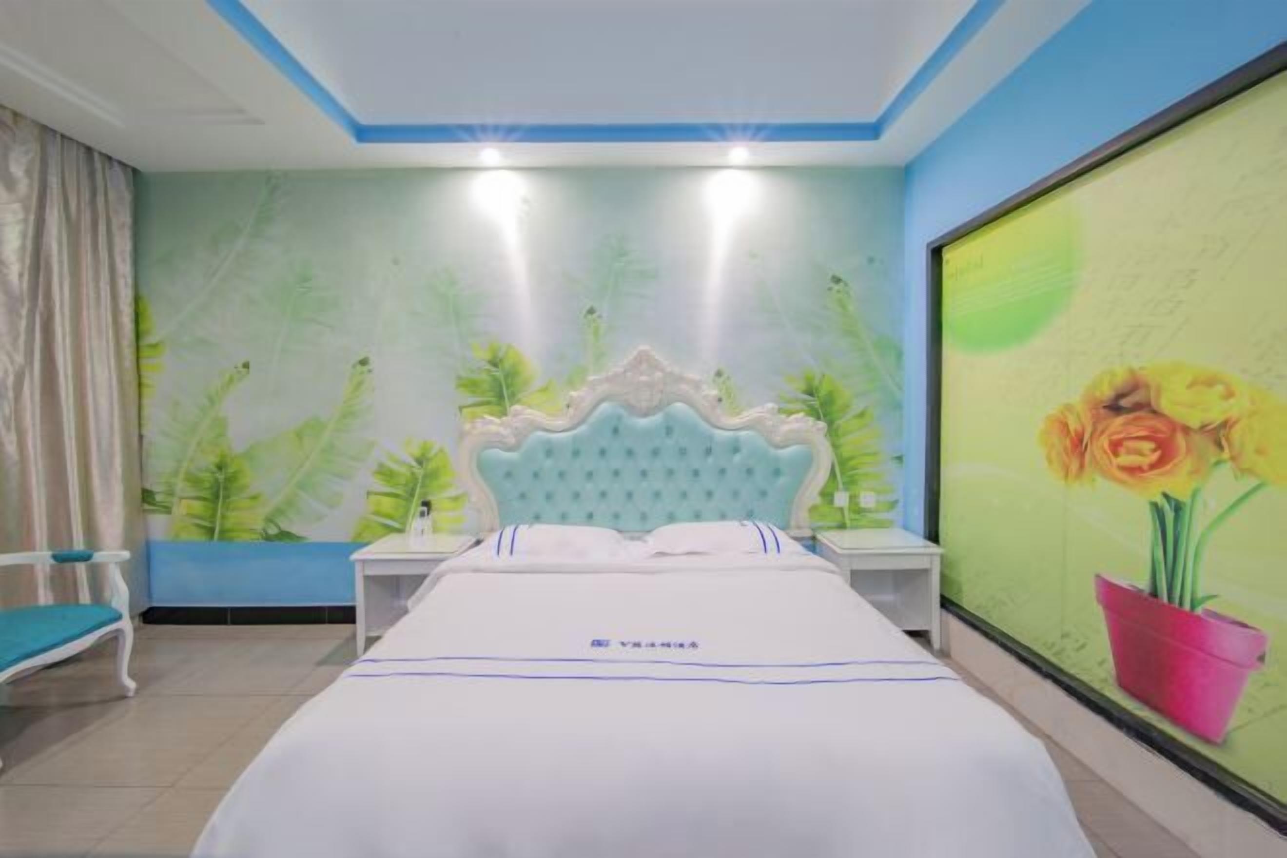 Habitació d'hotel amb un llit, una tauleta de nit, una cadira i una paret amb un mural floral.