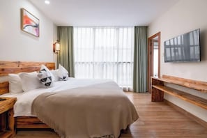 A hotel room with a large bed, wooden headboard, a flat-screen TV mounted on the wall, and a bench along the window. - Jiayan Runguo Hotel (Danzhou Summer Square Branch) (Danzhou)