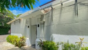A white building with a covered entrance and a door, surrounded by greenery. - The Lavana Villa Abimanyu 3 Seminyak (Bali)