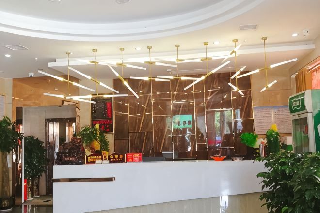 Un mostrador de recepción moderno con una encimera blanca, lámparas colgantes y una pantalla digital.