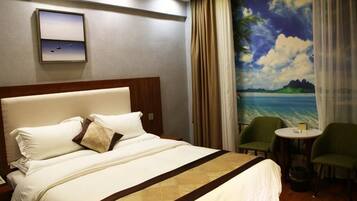 Una habitación de hotel con cama, una mesita, dos sillas, un cuadro de una playa y un marco en la pared.