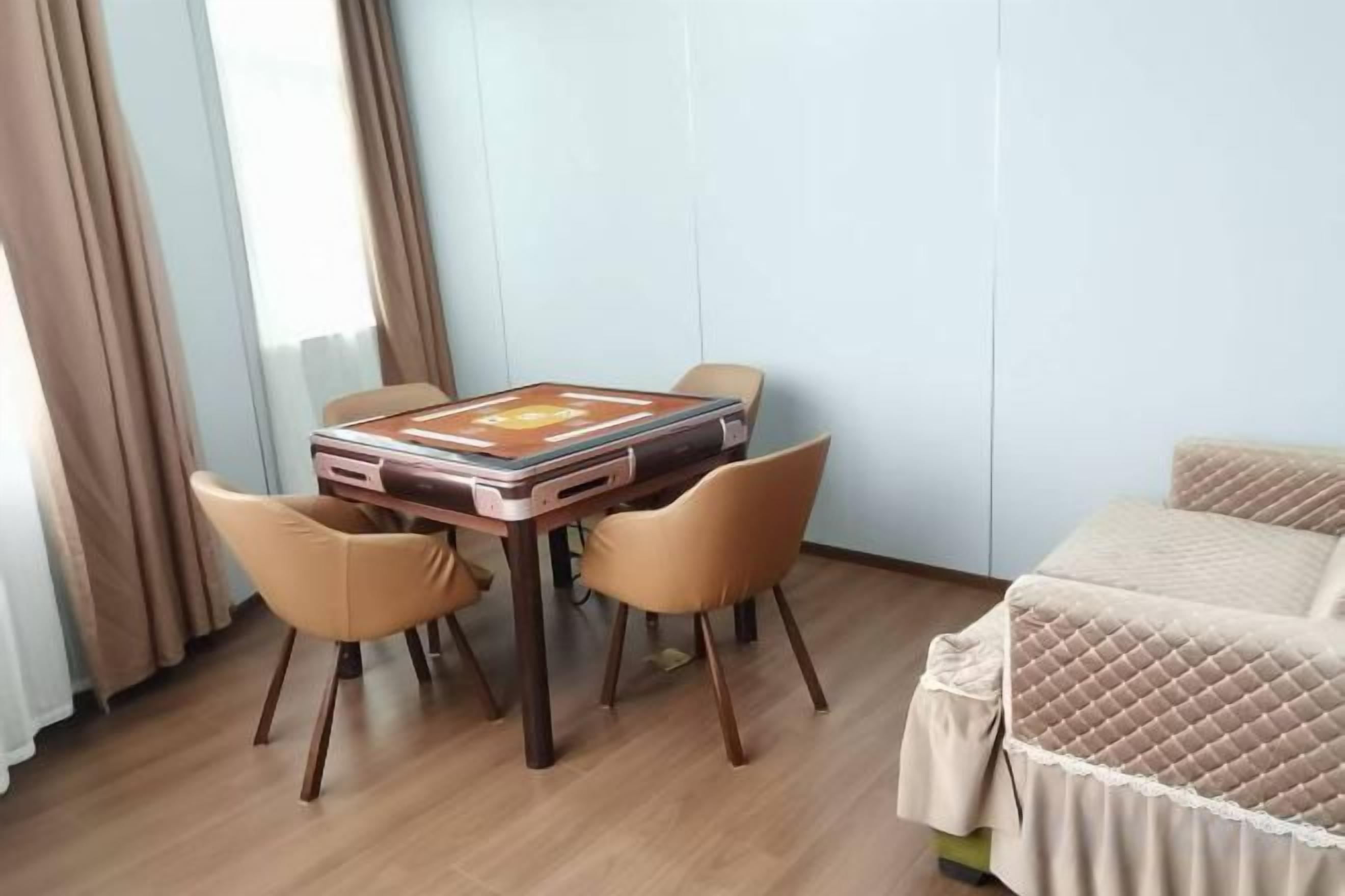 A room with a bed, a table with chairs, and a window with curtains.