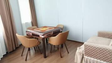 A room with a bed, a table with chairs, and a window with curtains.