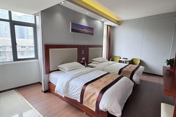 A hotel room with two beds, a large window, a painting on the wall, and a small table with a chair. - Furong Hotel (Qidong)