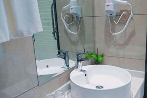 A bathroom with a white sink, a mirror, and a handheld showerhead. - Furong Hotel (Qidong)