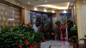 A hotel lobby with a curved ceiling, large windows, and potted plants. - Furong Hotel (Qidong)