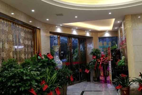 A hotel lobby with a curved ceiling, large windows, and potted plants. - Furong Hotel (Qidong)