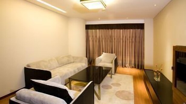 A modern living room with a sofa, armchair, and a glass coffee table. - Dongfang Jinzuo Apartment Hotel (Hangzhou)