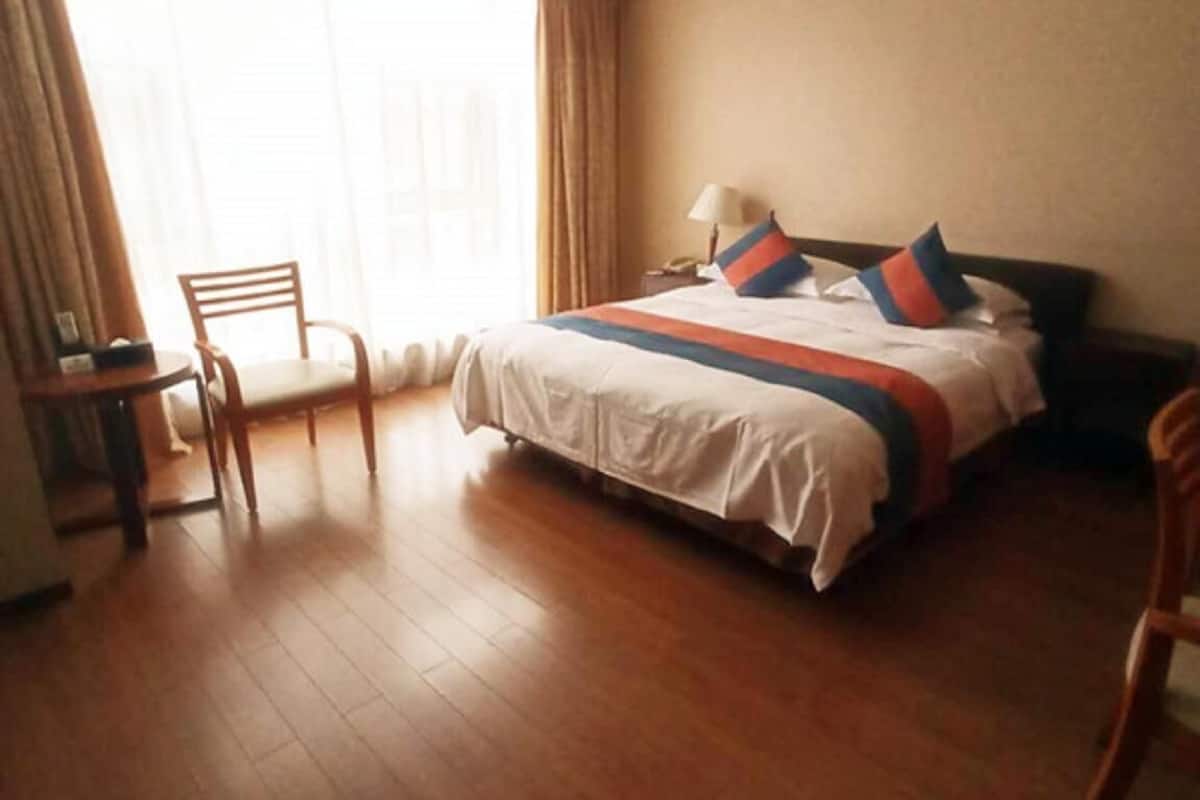 Una habitación de hotel con cama, una silla, un escritorio y un ventanal grande.