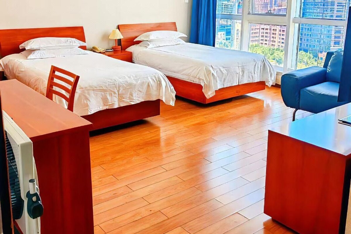 A hotel room with two beds, a desk, and a chair.