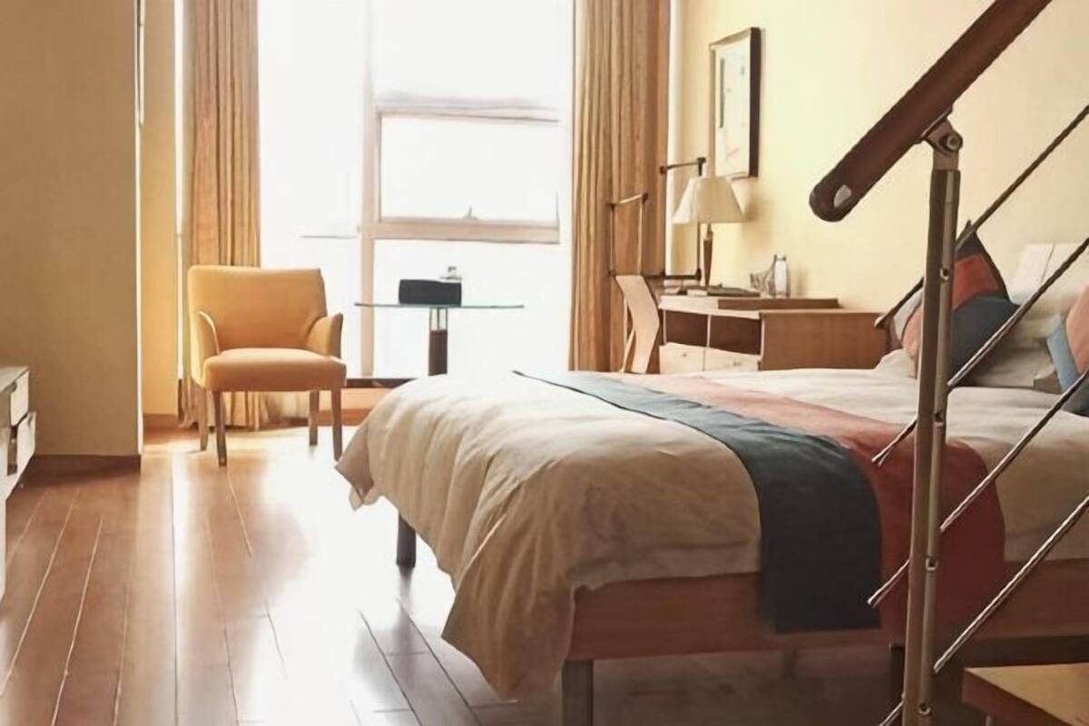Una habitación de hotel con cama, una silla, un escritorio y ventana.