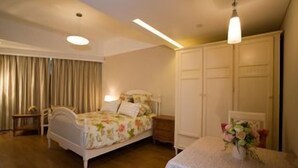 A bedroom with a bed, bedside tables, a dresser, a desk, and a chair. - Dongfang Jinzuo Apartment Hotel (Hangzhou)