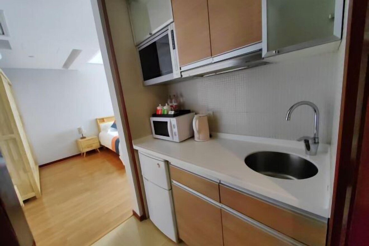 A compact kitchen with a microwave, sink, and cabinets.