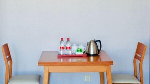 A wooden table with a tray holding bottles, a mug, and a kettle. Two wooden chairs are positioned on either side of the table. - Dongfang Jinzuo Apartment Hotel (Hangzhou)
