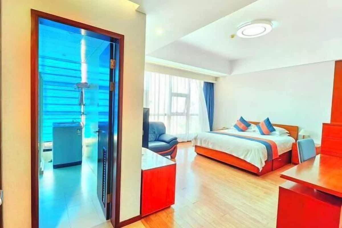 Habitación de hotel con cama, escritorio, silla, ventana y puerta que da a un baño.