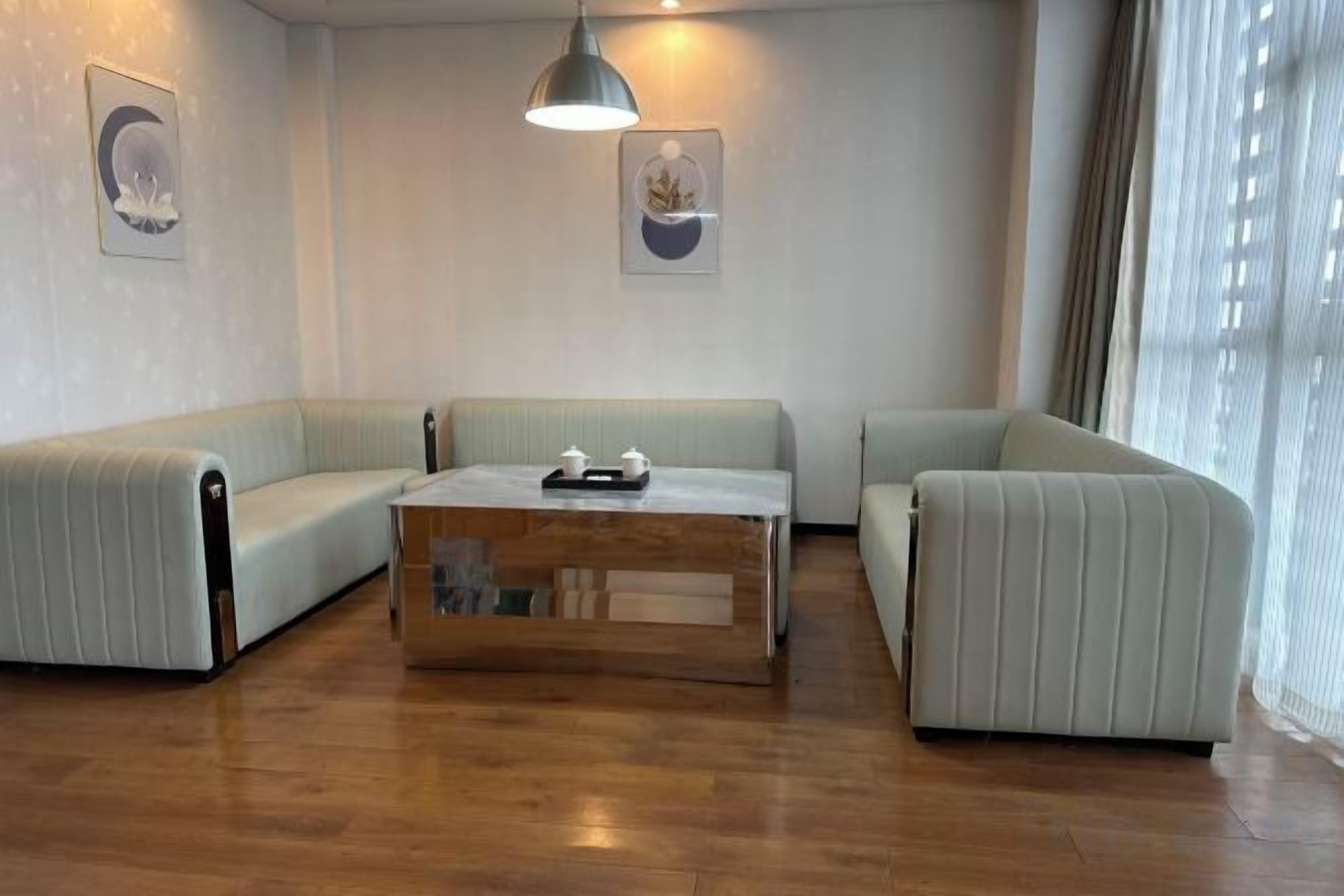 A modern living room with a wooden coffee table, two sofas, and a pendant light.