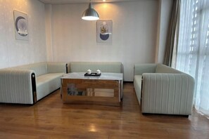 A modern living room with a wooden coffee table, two sofas, and a pendant light. - Tianhai Hotel (Jiujiang The Second Yangtze River Bridge Harbor) (Jiujiang)