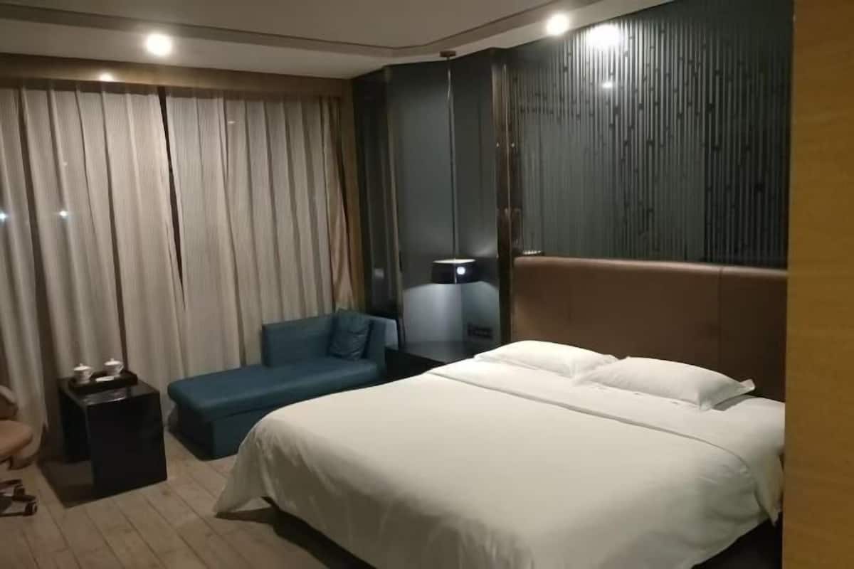 A hotel room with a large bed, a blue sofa, a small table, and a mirror.