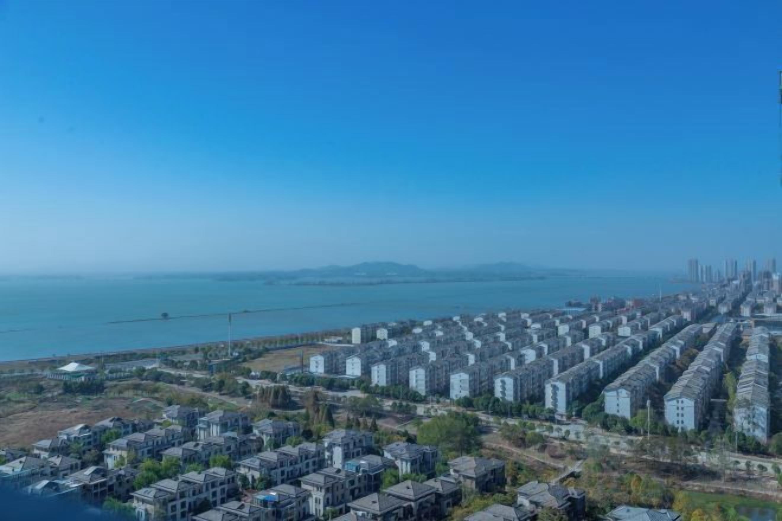 Un quartier résidentiel situé sur la côte, avec de grands immeubles, un ciel dégagé et une vue sur la mer.