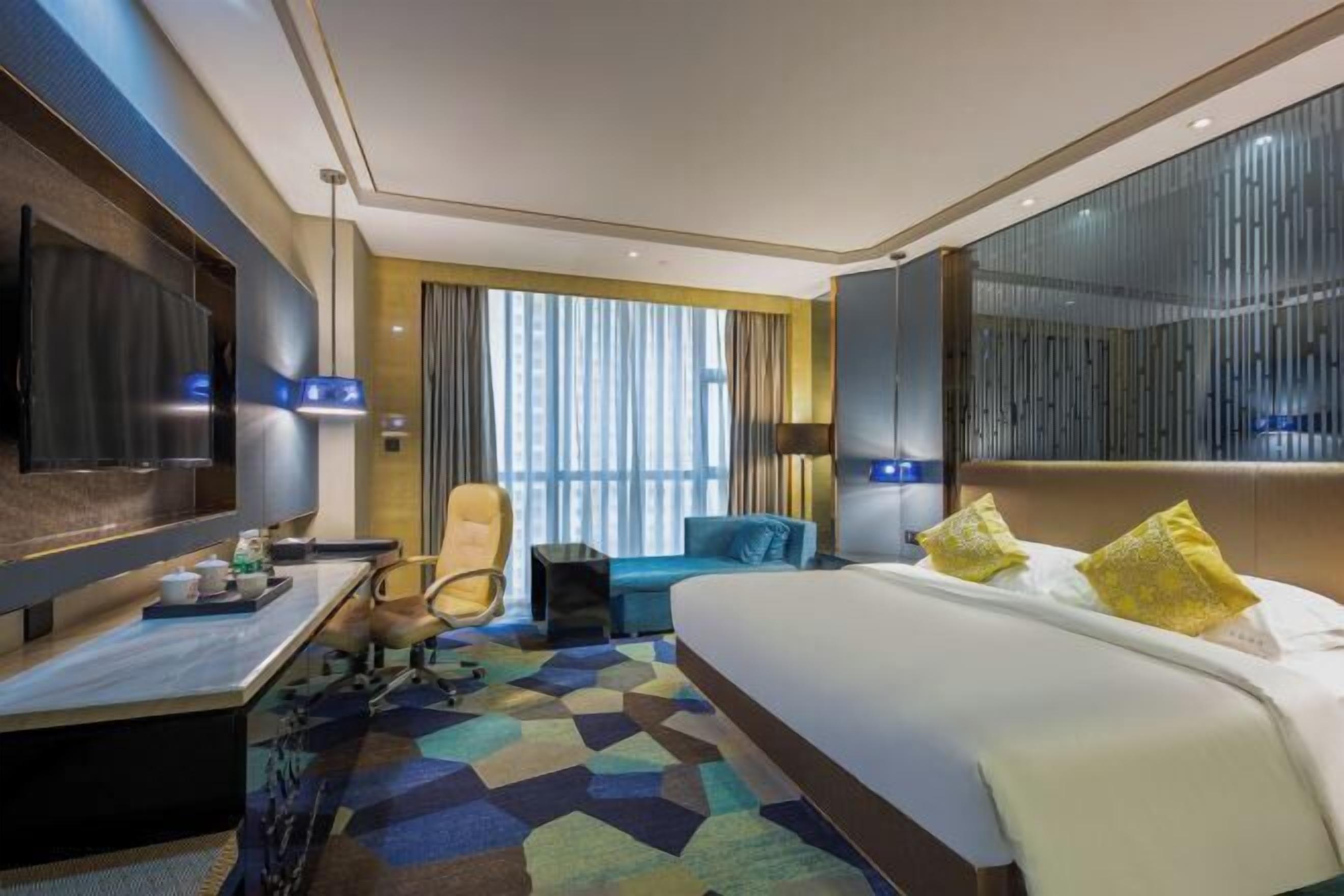 Una habitación de hotel moderna con una cama grande, un escritorio, una silla y un televisor.