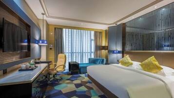 A modern hotel room with a large bed, a desk, a chair, and a TV.