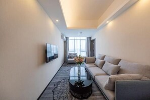 A modern hotel room with a sofa, a coffee table, and a TV on the wall. - XiDi Hotel (Shenzhen)