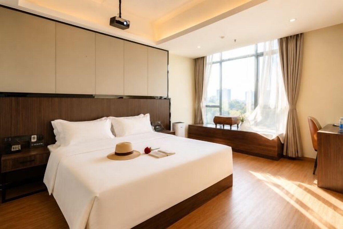 A hotel room with a large bed, a desk, and a view of the city.