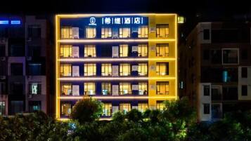 Edifici d'hotel de diverses plantes amb cartells il·luminats i finestres.