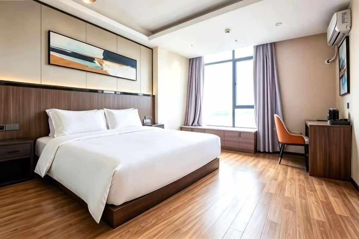 A modern hotel room with a large bed, a desk, and a chair.