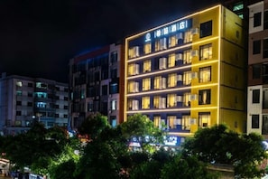 A multi-story hotel with illuminated windows and a prominent sign. - XiDi Hotel (Shenzhen)