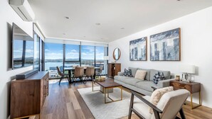 Una sala de estar moderna con un ventanal grande, un sofá, una mesita de centro y un comedor con sillas y una mesa.