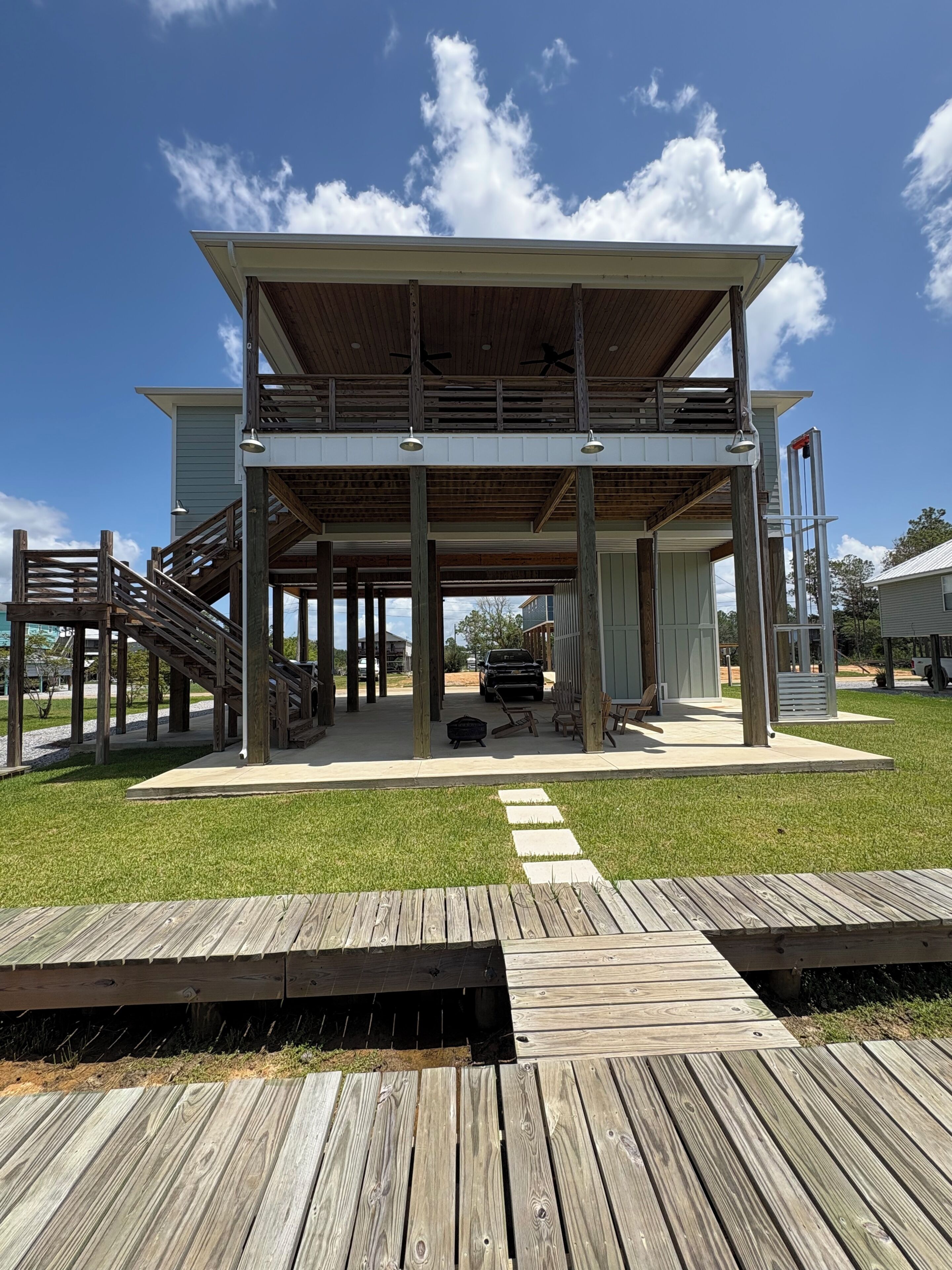 Une construction en bois à deux étages, dotée d’un balcon, d’un espace salon extérieur et d’une terrasse.