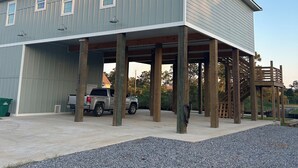 A two-story building with a covered parking area and a gravel driveway.