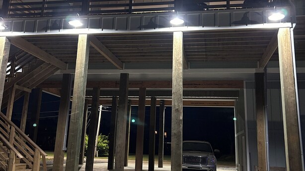 A modern building with a covered parking area, wooden beams, and a car parked inside.