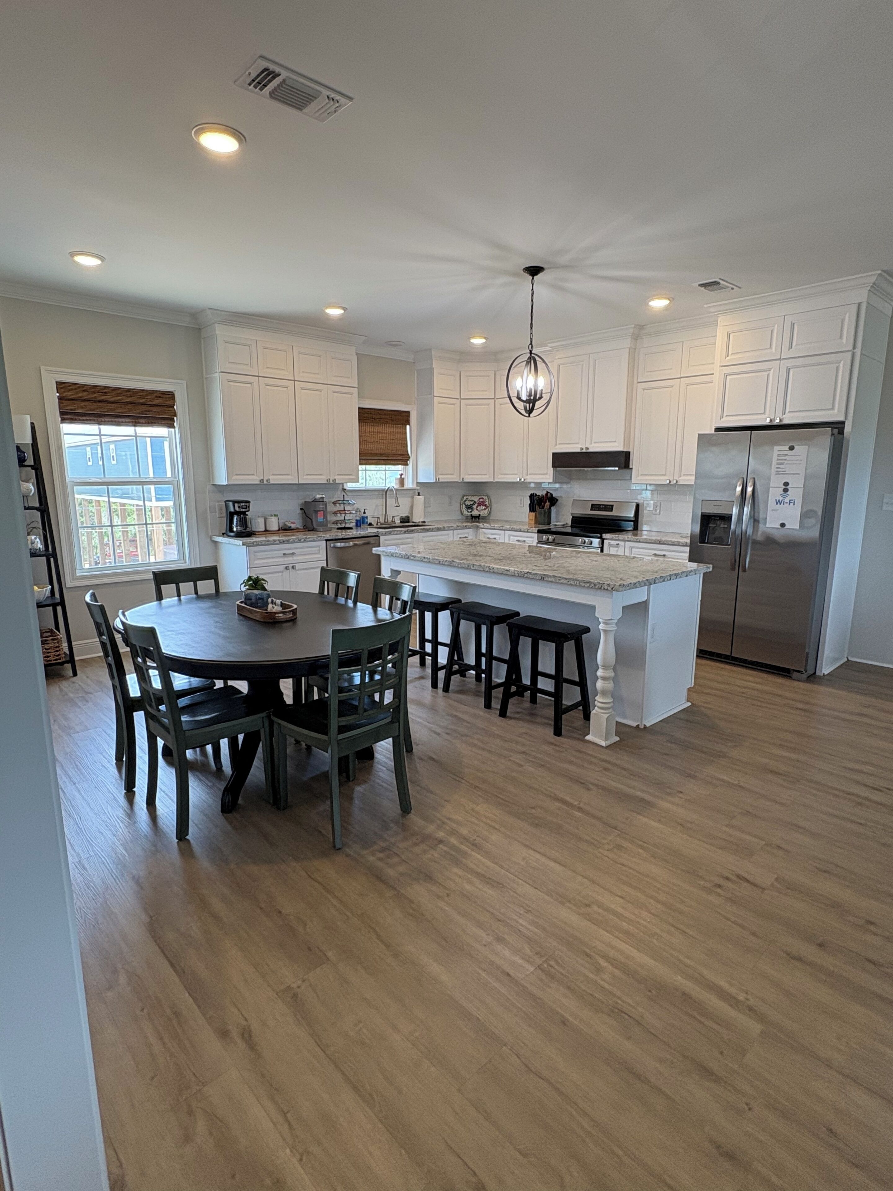 A modern kitchen with white cabinets, a central island, and a stainless steel refrigerator.