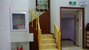 Una escalera con barandillas de madera y un extintor en el suelo.