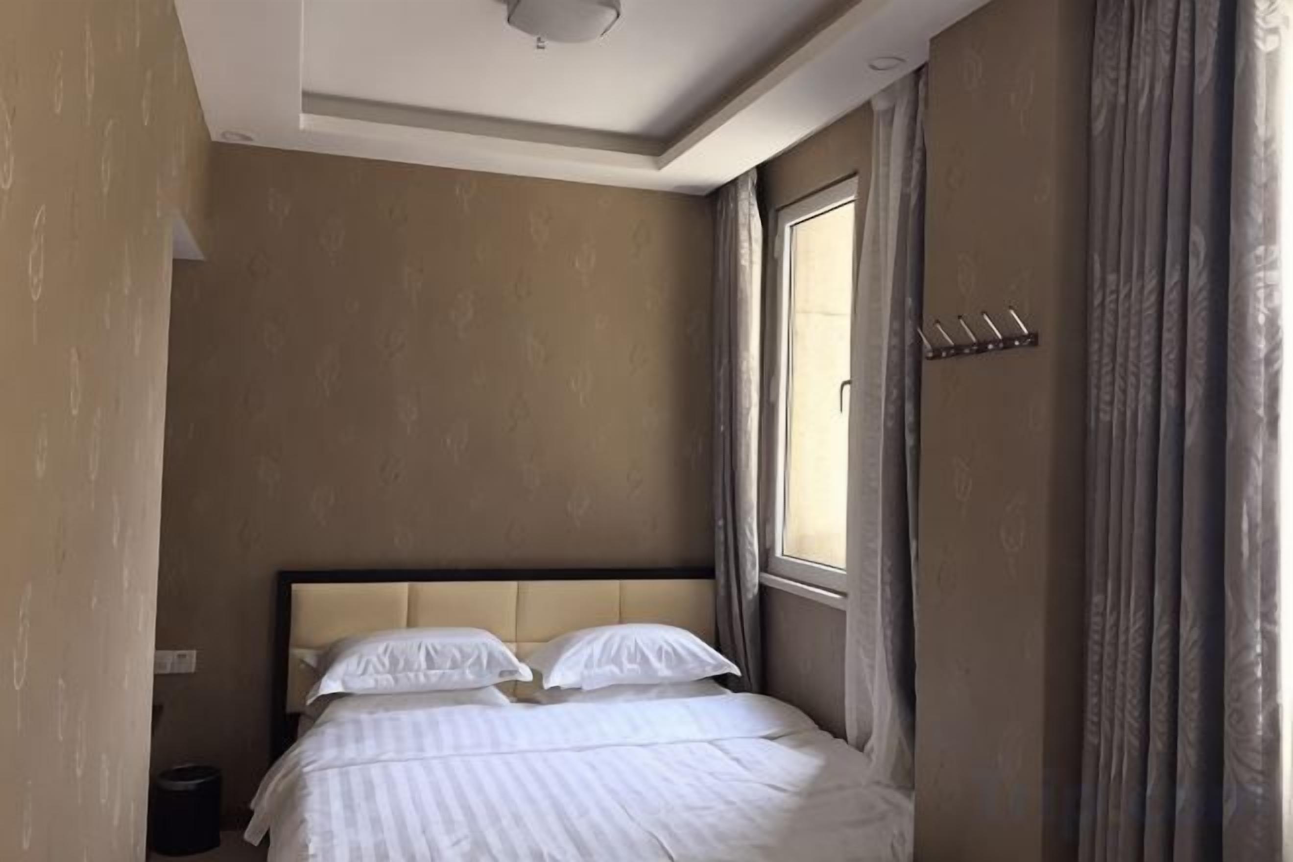 Ein Hotelzimmer mit Bett, Fenster und Kleiderhaken.